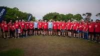 A group of runners with mostly red T-shirts stands in a semicircle.