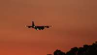 A plane lands in the sunset.