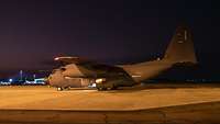 A transport plane in spotlights at an airfield.