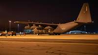 A transport plane in spotlights at an airfield.