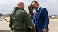 Three people stand on the air base and shake hands