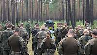 Soldaten und ein Militärpfarrer stehen im Wald