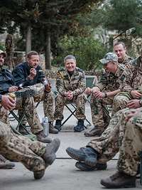 Eine Soldatin sitzt auf einen Campingstuhl in der Mitte von Soldaten, alle lächeln und unterhalten sich