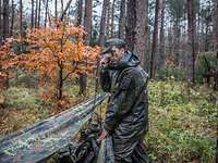 Ein Soldat im Wald am Funkgerät.