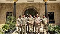 Gruppenfoto. Mehrere Soldaten verschiedener Nationen stehen nebeneinander vor einem Gebäude.