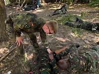 Tansanische Soldaten liegen auf dem Boden und legen sich gegenseitig ein Tourniquet an.