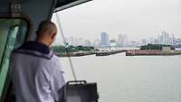 Ein Mann in Uniform steht auf einem Schiff mit Blick auf die Stadt Incheon.