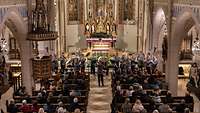 Musikerinnen und Musiker spielen mit Instrumenten vor einem Altar in einer Kirche.