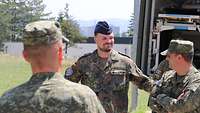 Oberstabsarzt und kosovarischer Oberst im Gespräch. Im Hintergrund ein militärischer Rettungswagen.