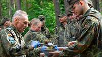 Ein älterer Reservist schenkt mit einer Kelle einem jungen Reservisten Suppe aus.