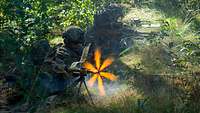 Vier Soldaten in einer Waldstellung eröffnen das Feuer mit MG5 und G36, Mündungsfeuer entsteht.