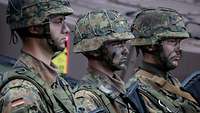 Three soldiers lined up with camouflage make-up