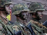 Three soldiers lined up with camouflage make-up