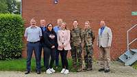 Gruppenbild mit acht Personen, davon zwei weibliche in Uniform, vor einem Dienstgebäude