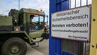 Ein militärischer Lkw durchquert ein Kasernentor. An dem Tor hängt ein Warnschild der Kaserne.