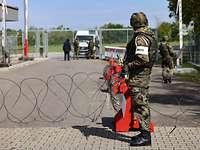 Ein Soldat an einer Drahtsperre beobachtet, wie Soldaten am Kasernentor ein Fahrzeug kontrollieren.