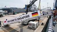 An einer Stelling ist ein Banner mit der Aufschrift „Welcome to Singapore“ angebracht.