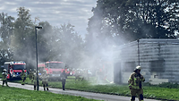 Feuerwehrleute gehen einen Weg entlang. Ihnen folgt ein Löschfahrzeug.