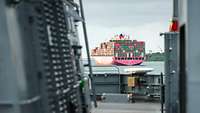 Blick auf eine Containerschiff von einem grauen Schiff aus