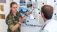 Zwei Soldaten stehen vor einem Whiteboard und besprechen die Stellflächen von Transportflugzeugen 