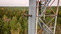 Ein Soldat seilt sich an der Steilwand eines Kletterturms ab