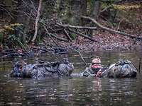 Zwei Soldaten schwimmen mit ihrer Ausrüstung durch einen Fluss.