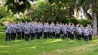 Militärmusiker stehen mit ihren Instrumenten auf einer Wiese