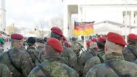 Deutsche Soldaten in Formation angetreten auf einem Platz vor einer Deutschlandflagge