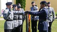 Soldatinnen und Soldaten halten ihre linke Hand auf der Truppenflagge und ihre rechte Hand zum Gelöbnis.