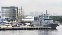 Ein graues Marineschiff hat an einer Pier in einem Hafen festgemacht.