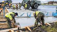 Mehrere Soldaten gießen ein Betonfundament