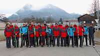 Mehrere Sportler stehen für ein Gruppenbild zusammen. Im Hintergrund ist ein Berg zu sehen.