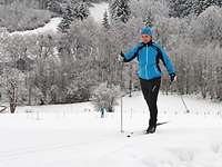 Zwei Sportler fahren auf Skiern durch ein verschneites Gelände