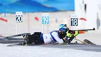 Ein Sportler mit Beinprothese liegt mit Gewehr im Anschlag im Schnee