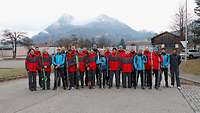 Mehrere Sportler stehen für ein Gruppenbild zusammen. Im Hintergrund sind Berge zu sehen.