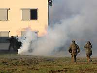 Mehrere Soldaten stürmen auf ein Gebäude zu. Vor ihnen ist Nebel.