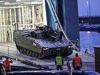 Soldiers unload a tank from a ship.