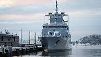 Ein graues Schiff der Deutschen Marine liegt an der Pier im verschneiten Oslo.