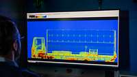 Ein Soldat sitzt vor einem Monitor und wertet die Röntgenaufnahme von einem LKW aus