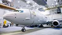 Ein weißes Flugzeug der Deutschen Marine steht in einem Hangar.