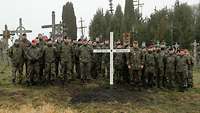 Viele Soldaten stehen hinter einem weißen Holzkreuz