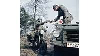 Historisches Foto: Ein militärischer Motorradfahrer übergibt ein Stück Papier an einen Soldaten