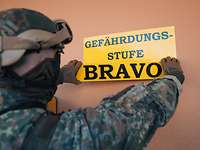 Ein Soldat befestigt ein Schild mit der Aufschrift „Gefährdungsstufe Bravo“ an einer Wand