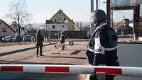 Am Kasernentor stehen Soldaten Wache auf der Zufahrtsstraße, am Pförtnerhäuschen und an der Schranke