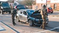 Zwei Soldaten durchsuchen ein Auto auf einer Straße