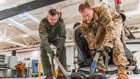 Ein US-amerikanischer und ein deutscher Soldat ordnen dicke Seile, die an einem Karabiner hängen.