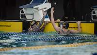 Zwei Sportler am Schwimmbeckenrand geben sich ein High Five