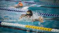 Ein Sportler mit Badekappe "GER" beim Brustschwimmen in einem Schwimmbecken