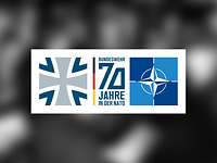 Das Logo „Bundeswehr 70 Jahre in der NATO“ auf einem unscharfen Schwarzweiß-Foto