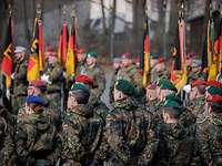 Viele deutsche Soldaten stehen bei einem Appell mit Truppenfahnen auf einem Platz in Formation.